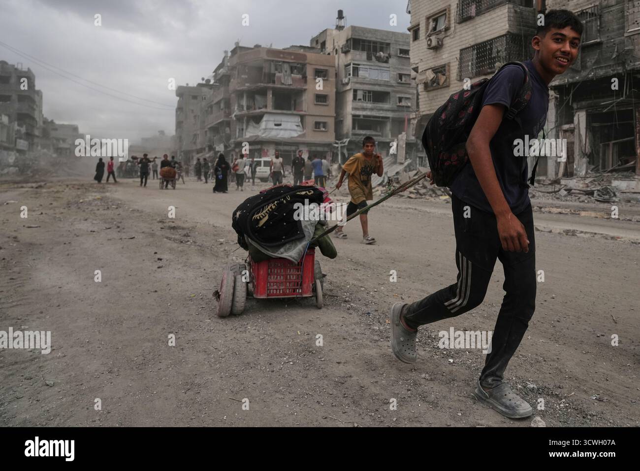 Displaced Palestinians walk with their belongings along the heavily ...