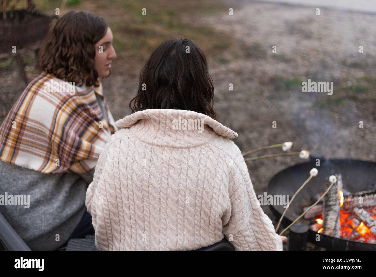 two young women roasting marshmallows over a campfire Stock Photo