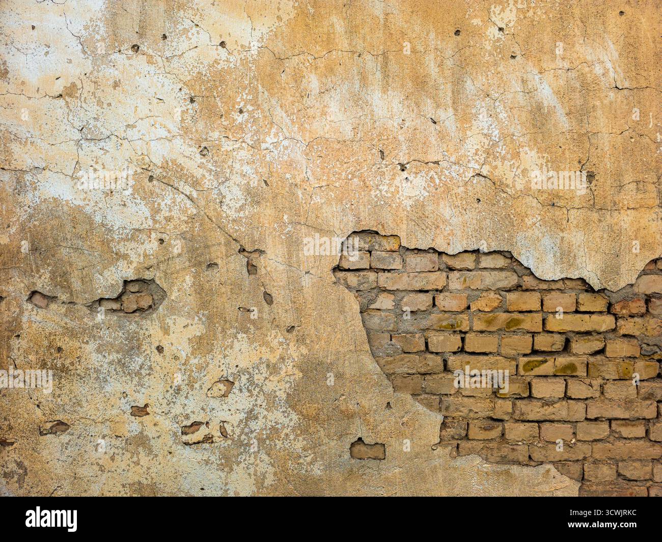 Old brick wall with peeling plaster and exposed bricks Stock Photo
