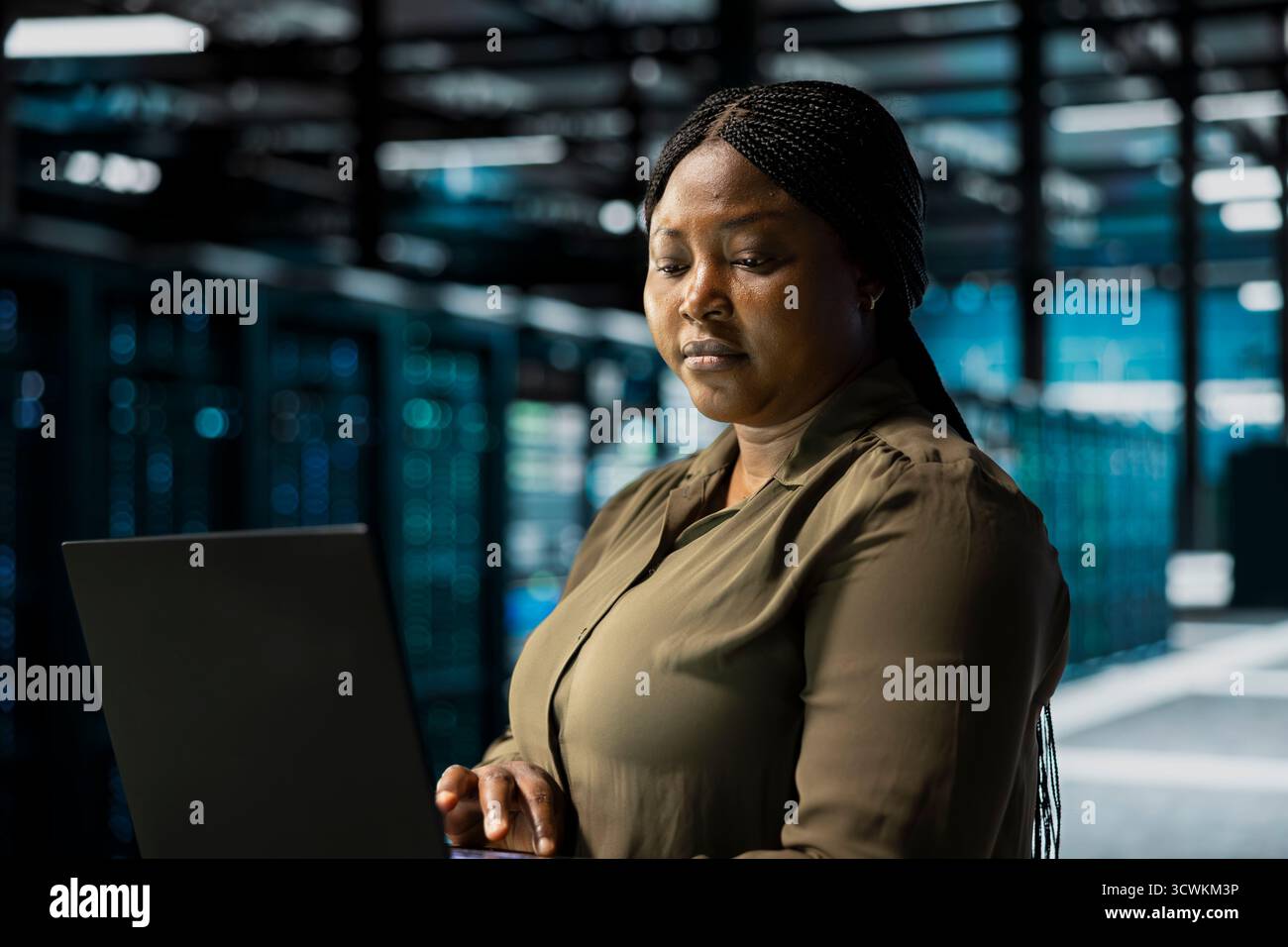 Data center programmer using laptop to optimize network infrastructure, planning capacity. IT expert managing server farm resources with notebook for improved reliability and uptime Stock Photo
