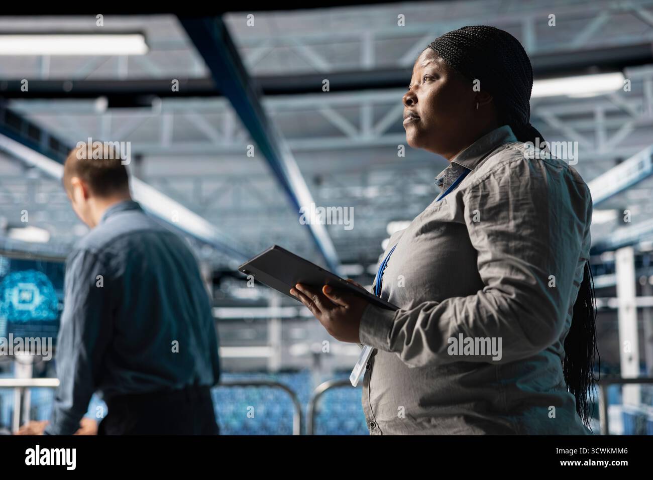 Server room infrastructure engineers scripting automated workflows using software on tablet. Teamworking data center programmers running predictive maintenance scans using device Stock Photo