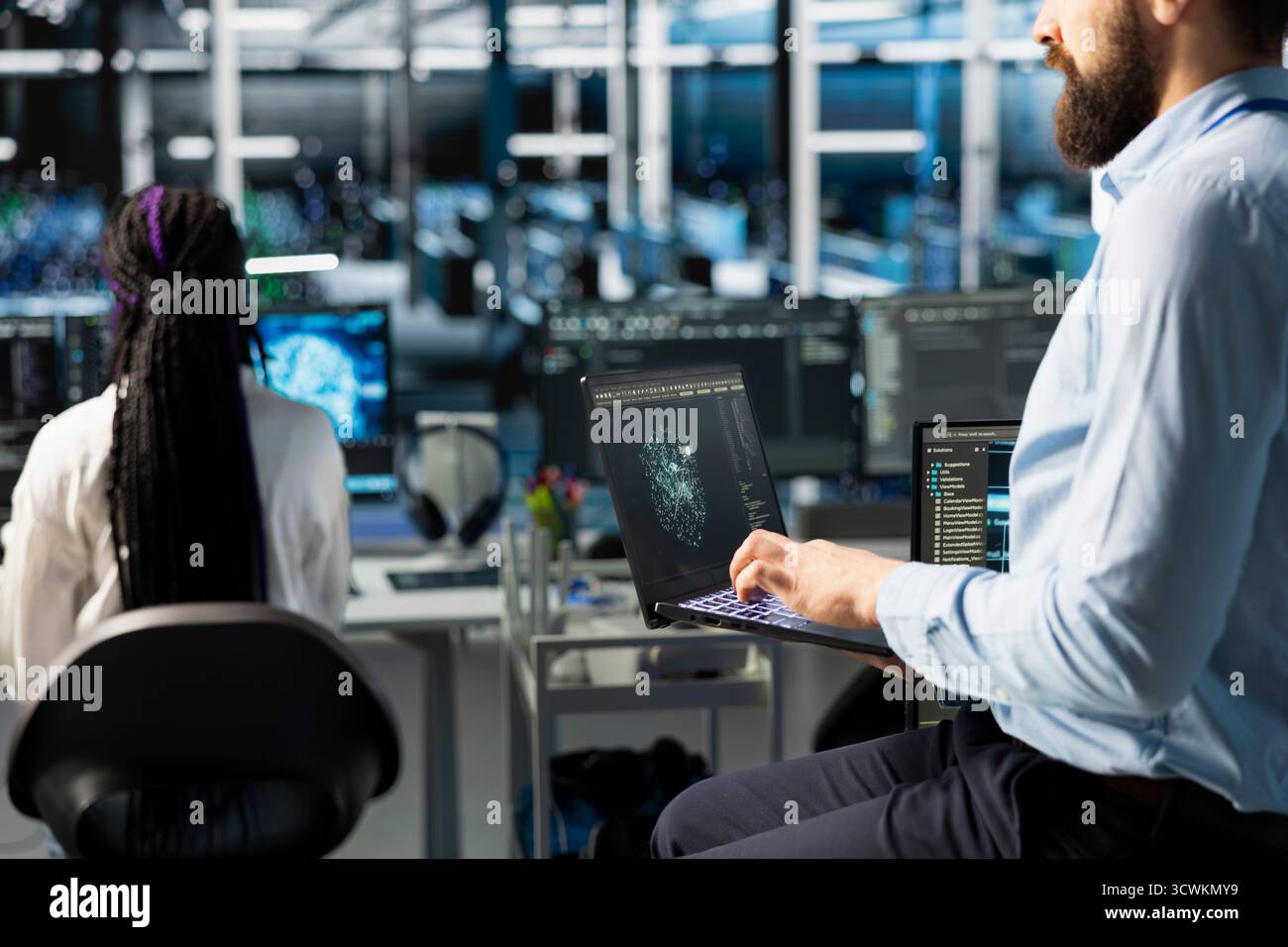 Network engineers in data center troubleshooting server connectivity issues using AI. Technicians in server room auditing systems for vulnerabilities using artificial intelligence Stock Photo