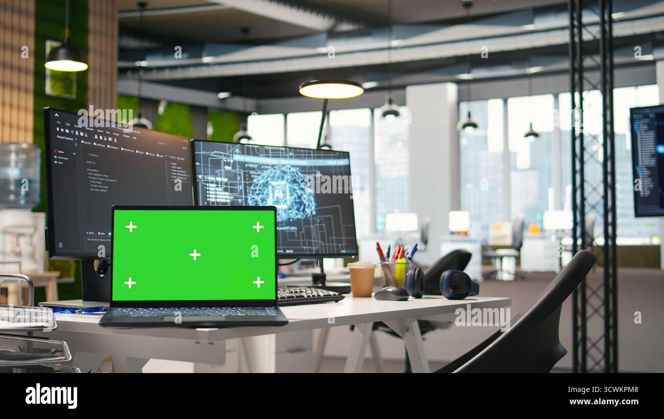 Green screen laptop and AI algorithms running on computer monitors in empty startup workspace deploying machine learning models. Mockup notebook and artificial intelligence coding platform in office Stock Photo