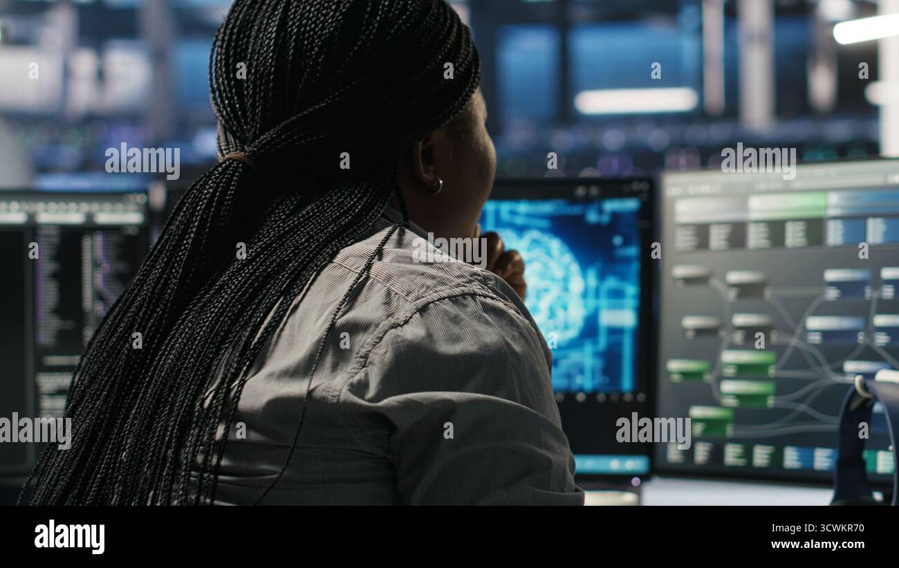 Data center software developer using artificial intelligence deep learning models to configure hardware. IT professional works on AI programming language in server farm, optimizing system, camera B Stock Photo