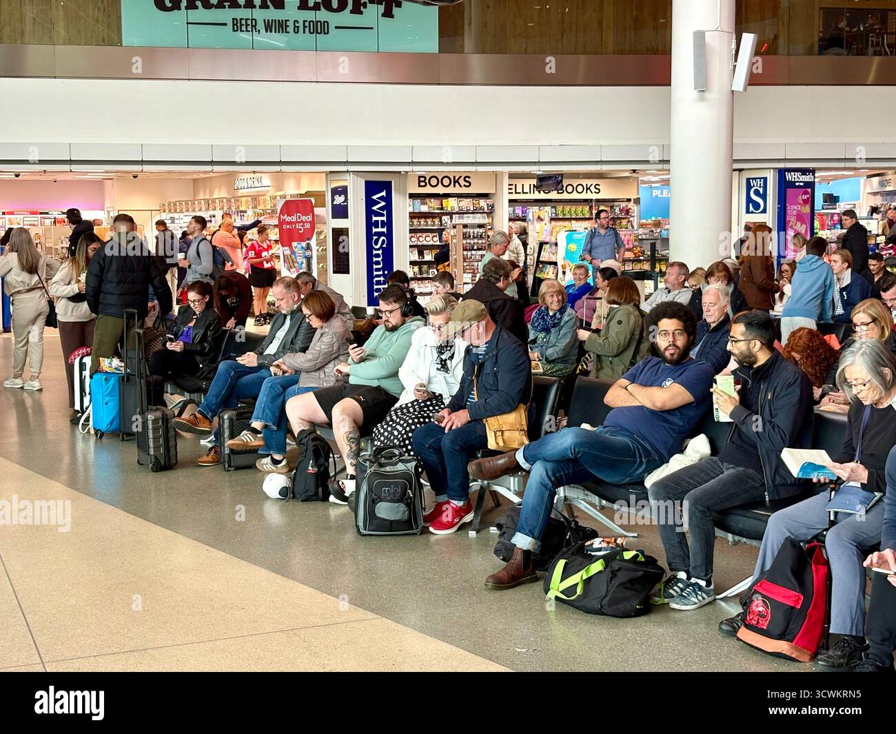 Manchester airport terminal 1 departures area, passengers sitting near the departure gates waiting for their overseas flights to be announced,England - Smartphone Captured Stock Image