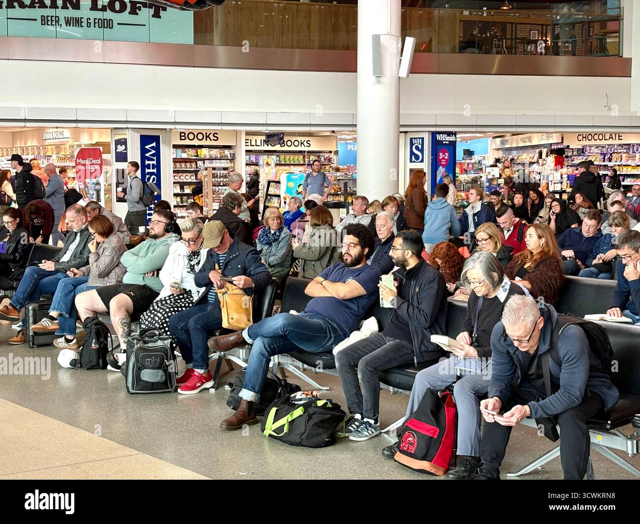 Manchester airport terminal 1 departures area, passengers sitting near the departure gates waiting for their overseas flights to be announced,England - Smartphone Captured Stock Image