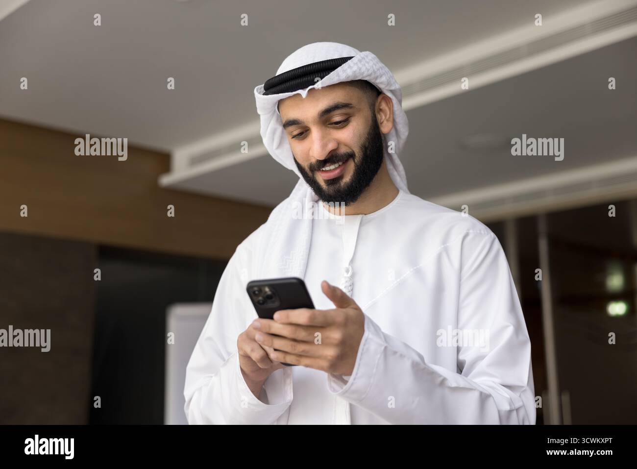 Smiling young middle eastern businessman hold smartphone read message text Stock Photo