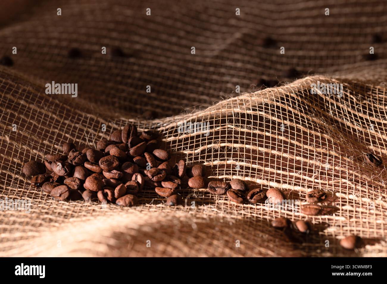 Whole roasted coffee beans on a burlap sack Stock Photo