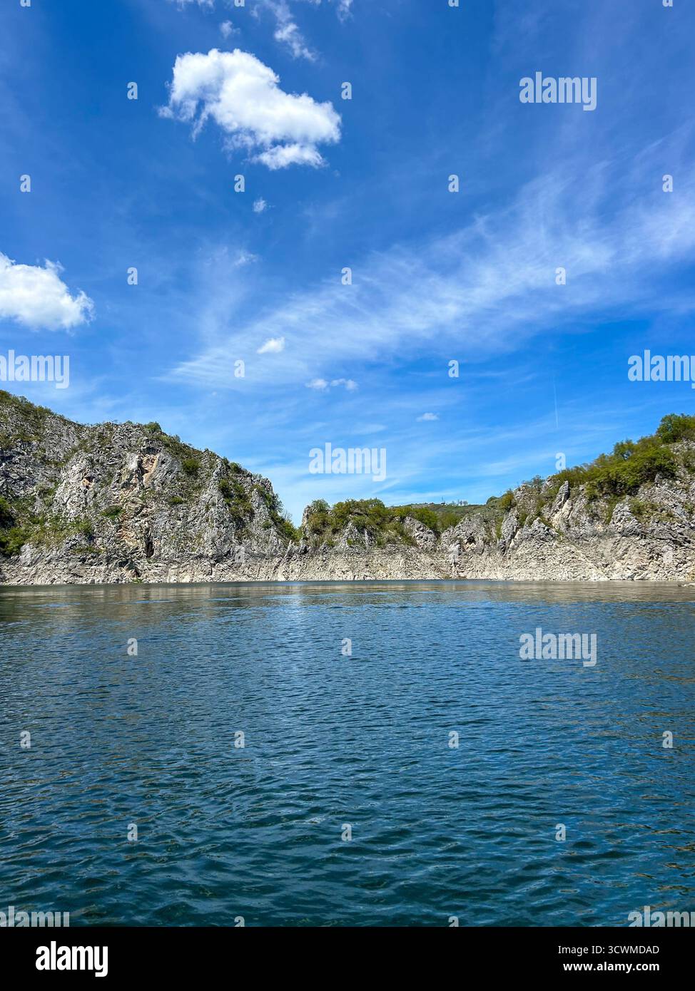 Tranquil view of Uvac Lake with crystal-clear water, rocky cliffs, and blue sky on a sunny day, showcasing the natural beauty of Serbia’s landscape. - Smartphone Captured Stock Image