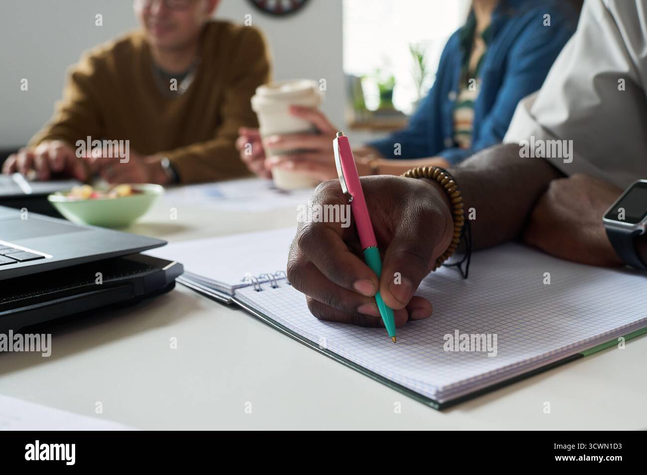 Multiethnic Team Collaborating and Taking Notes during Meeting Stock Photo