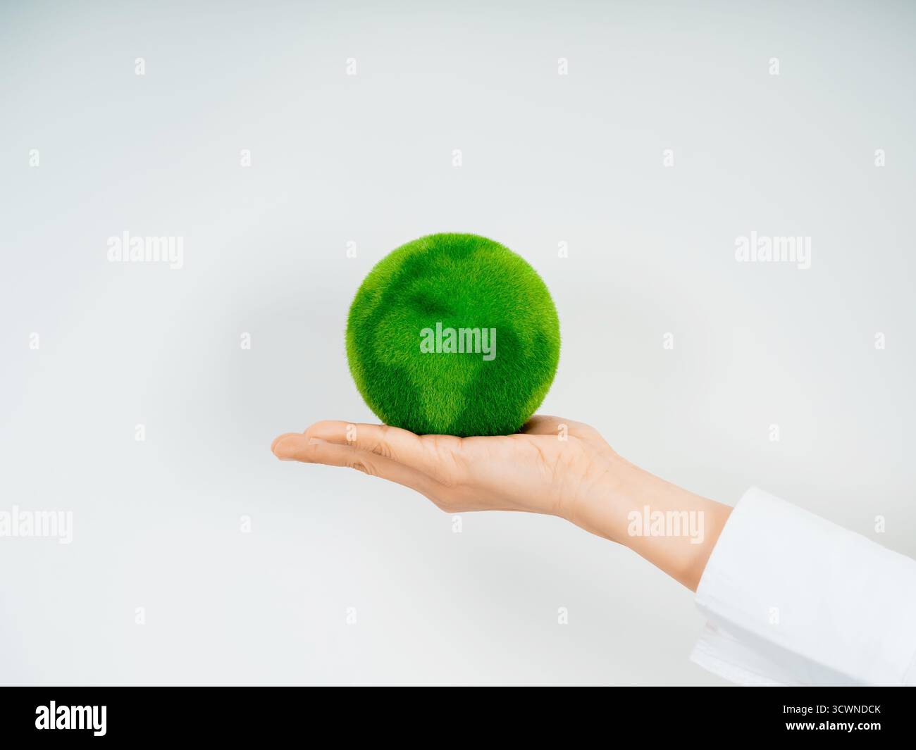 Human hand holding green grass globe representing the Earth on white ...