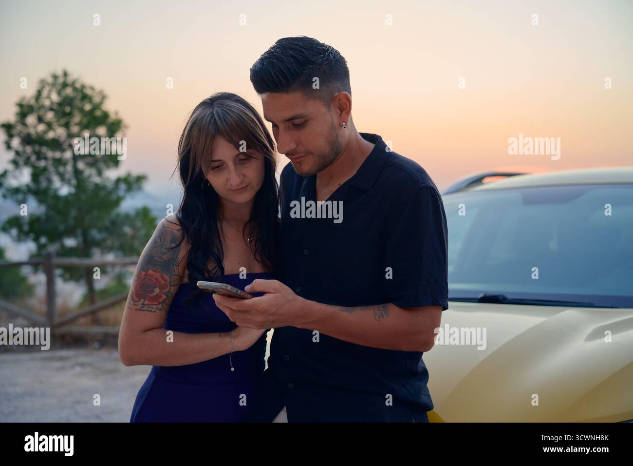 Young couple using smartphone together during sunset trip Stock Photo