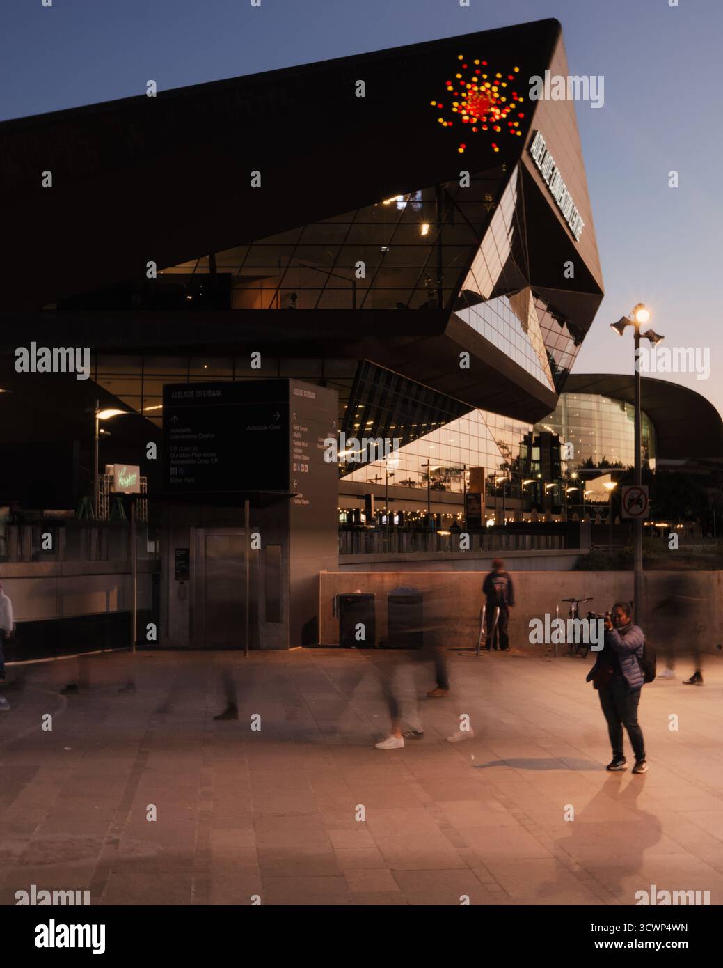 Long-exposure shot of the Adelaide Convention Centre; warm interior lights against the cool dusk sky create a dramatic, reflective mood. Stock Photo