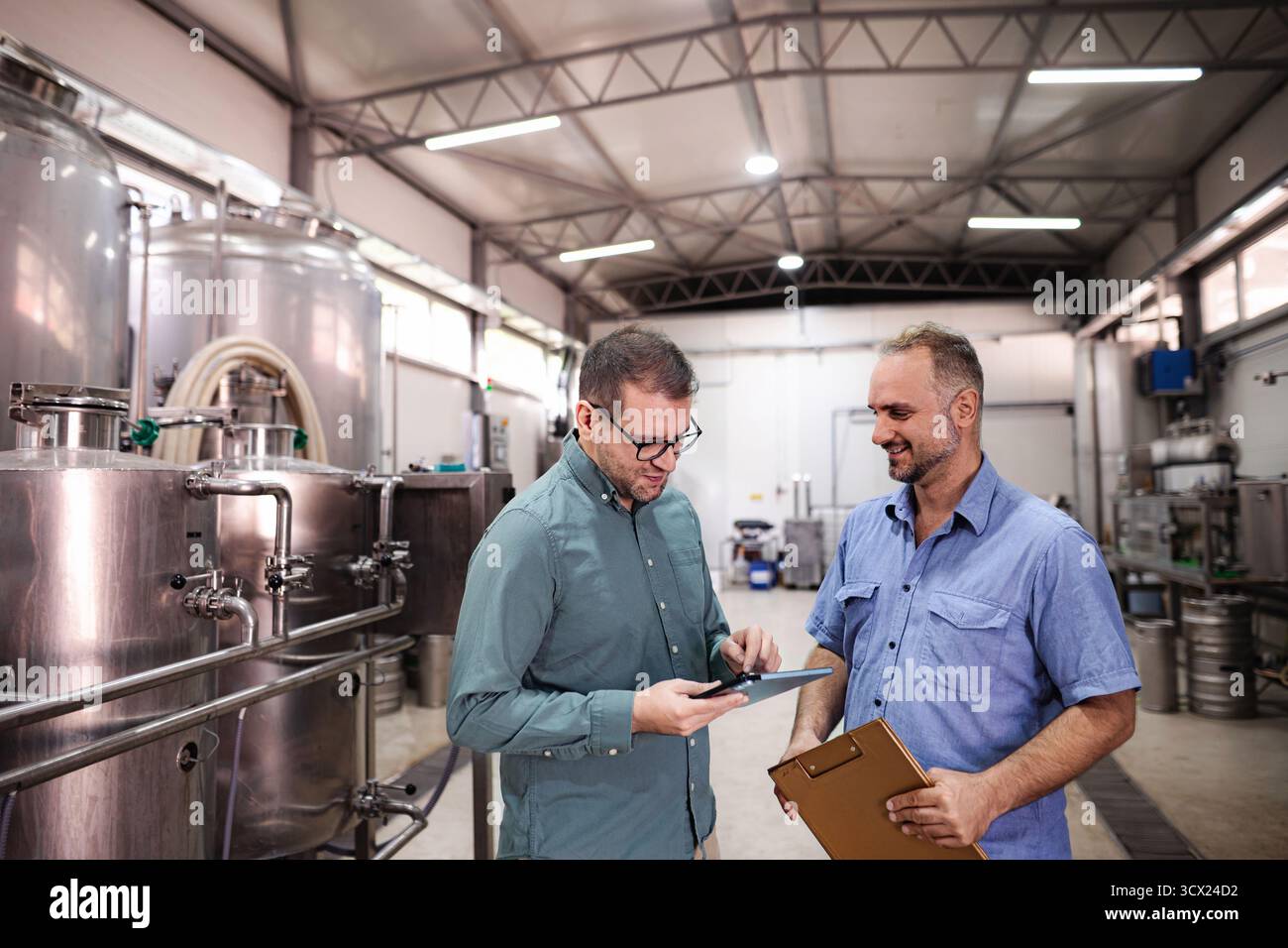 Brewery workers discussing production planning using digital tablet Stock Photo