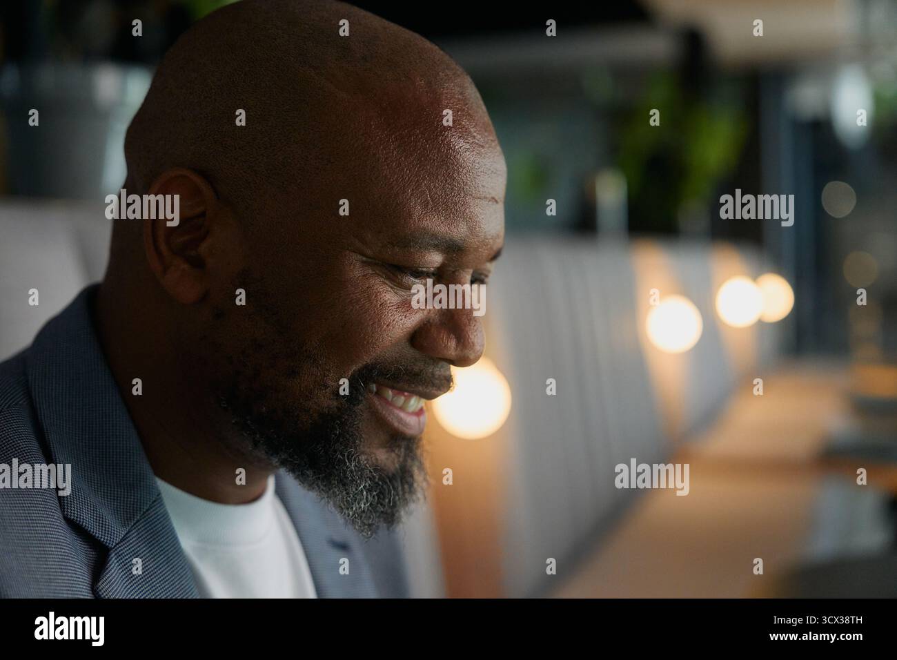 Closeup side view of bald mature businessman smiling while deep in thought in office Stock Photo