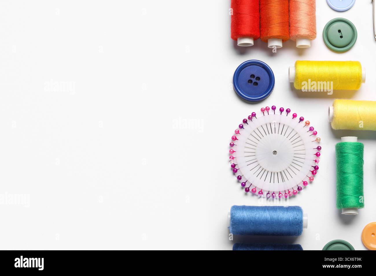 Composition with different thread spools, ball pins and buttons on white background, closeup Stock Photo