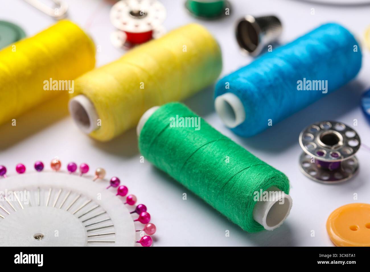 Composition with different thread spools and ball pins on white background, closeup Stock Photo