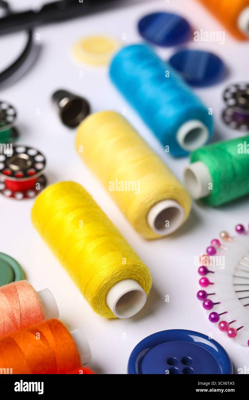 Composition with different thread spools and accessories on white background, closeup Stock Photo