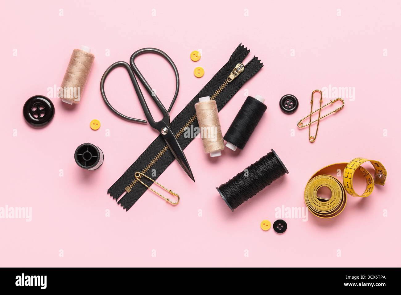 Composition with thread spools, scissors and buttons on pink background Stock Photo