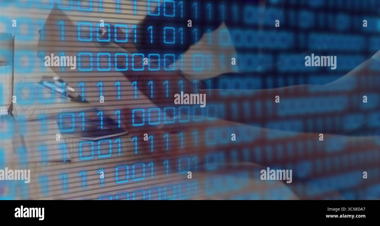 Man wearing button up shirt writing in notebook, typing on laptop at workspace, binary code overlay Stock Photo