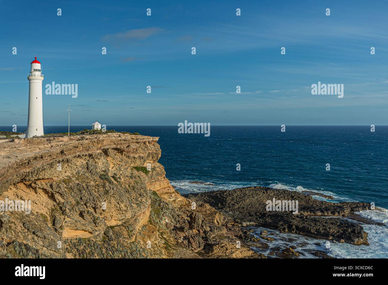Tall white lighthouse with a red top stands prominently on rugged ...