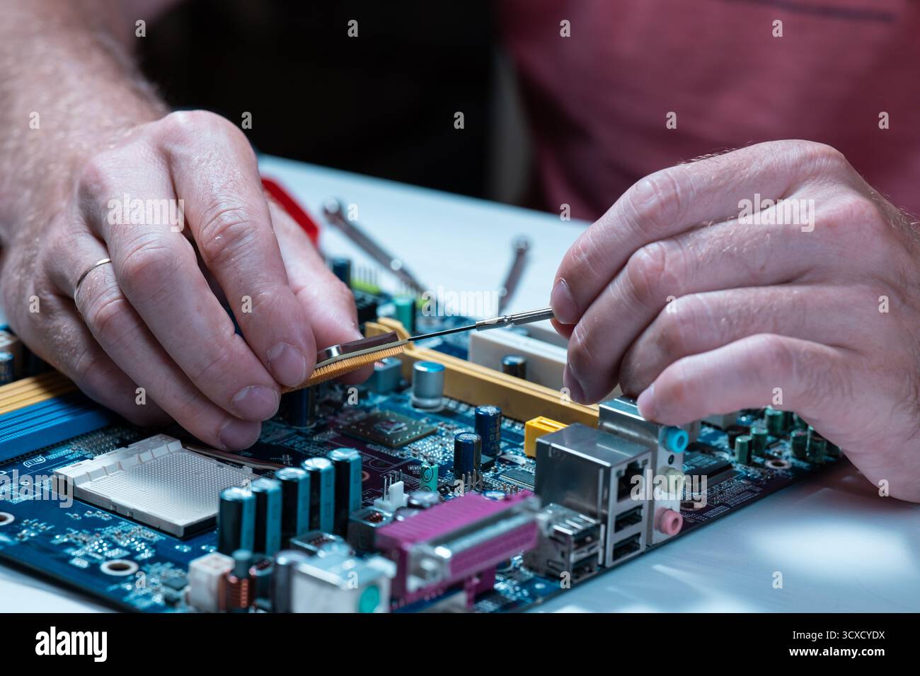 A master repairs a motherboard from a computer Stock Photo