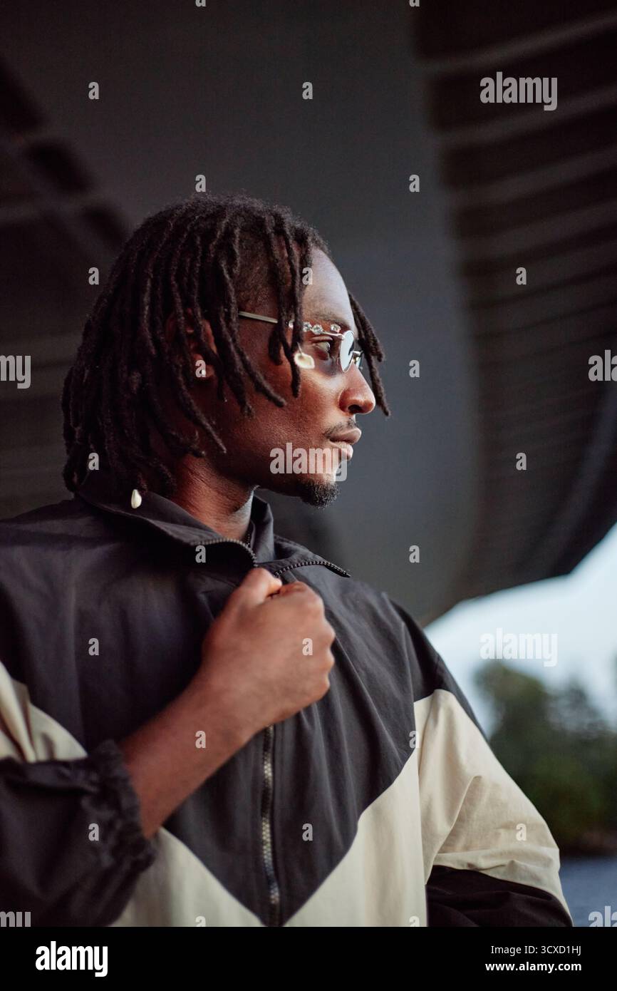 Young Adult Black Man Standing Outdoors Looking Away with Thoughtful Expression Stock Photo