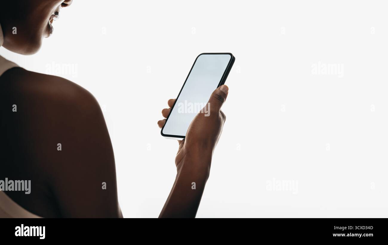 Close-up of a woman holding a smartphone and interacting with its screen in a minimal setting focusing on modern technology and connection Stock Photo