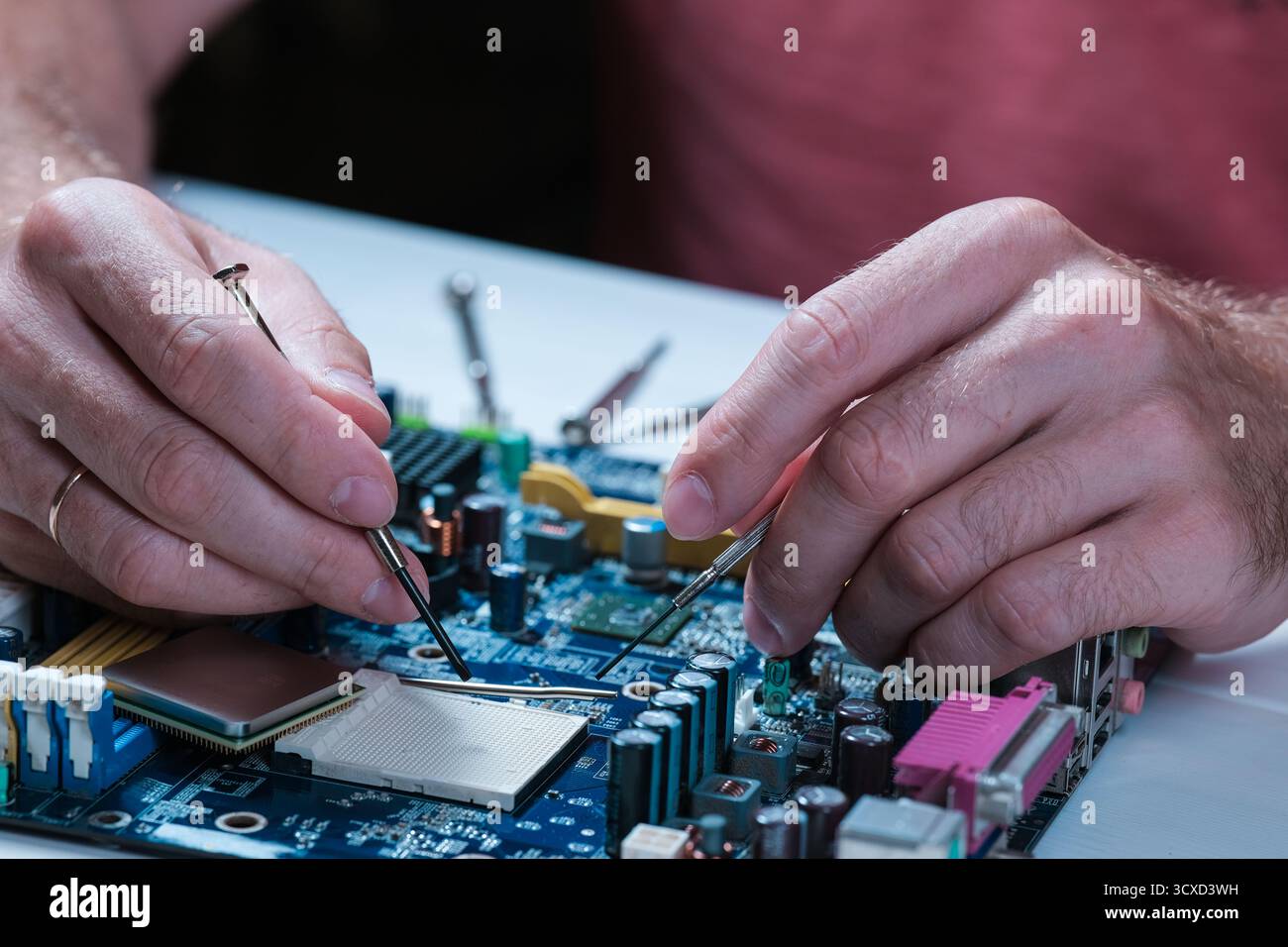 A master repairs a motherboard from a computer Stock Photo