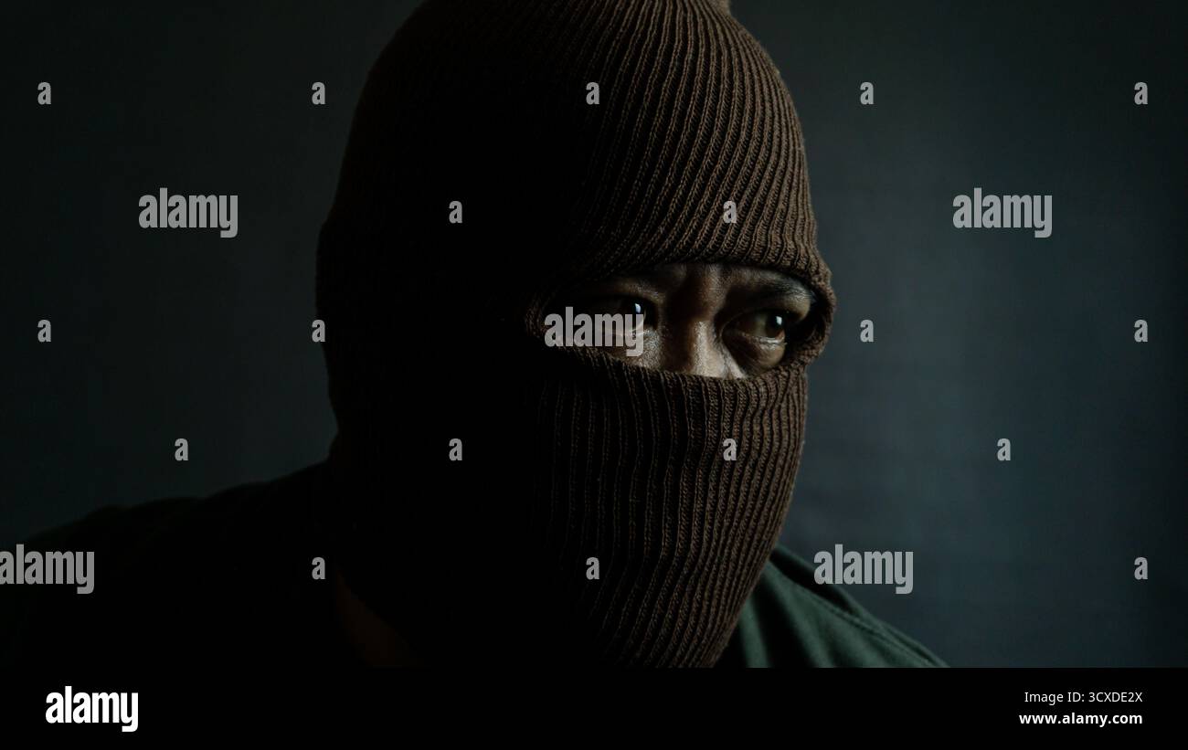 Male subject with brown fabric eye mask fully worn on face, isolated on black, suggesting secrecy, mystery, or covert identity with moody lighting Stock Photo