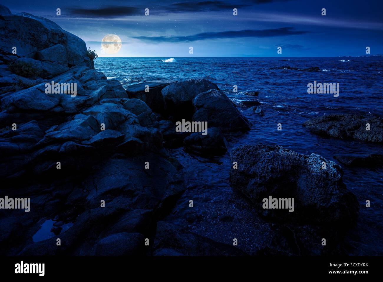 sea coast with rocks and boulders at night. calm summer vacation background at the seashore. wonderful scene for relax and leisure at the seaside in f Stock Photo