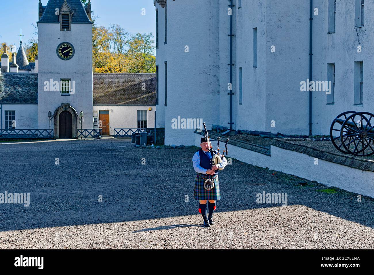 Blair Castle Perthshire Scotland a lone piper playing the bagpipes and trees in Autumn Stock Photo