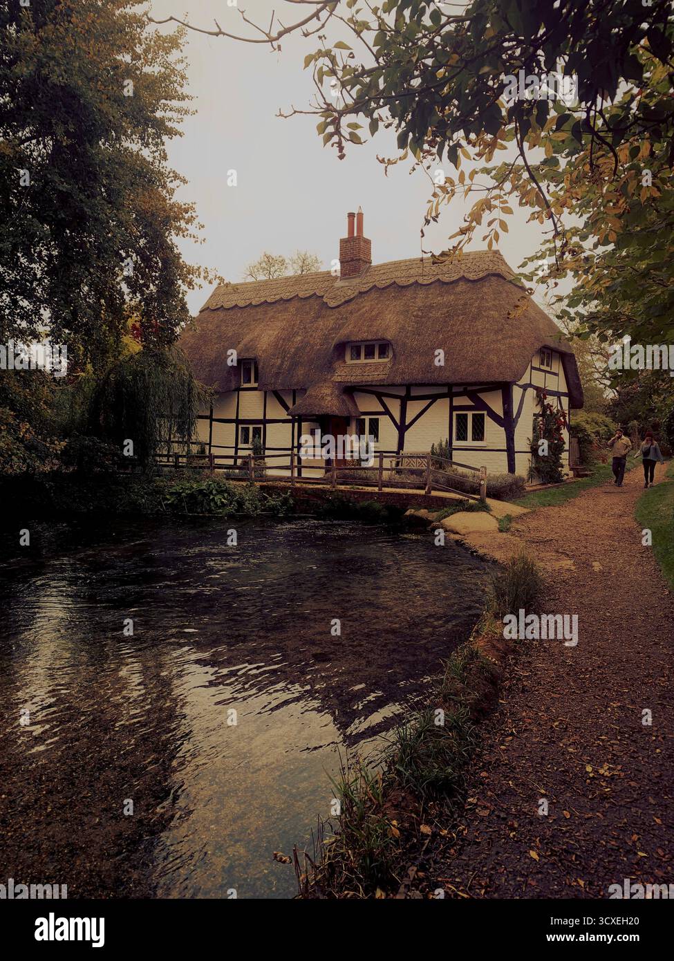 A thatched roof cottage over a chalk strem in hampshire England UK Stock Photo