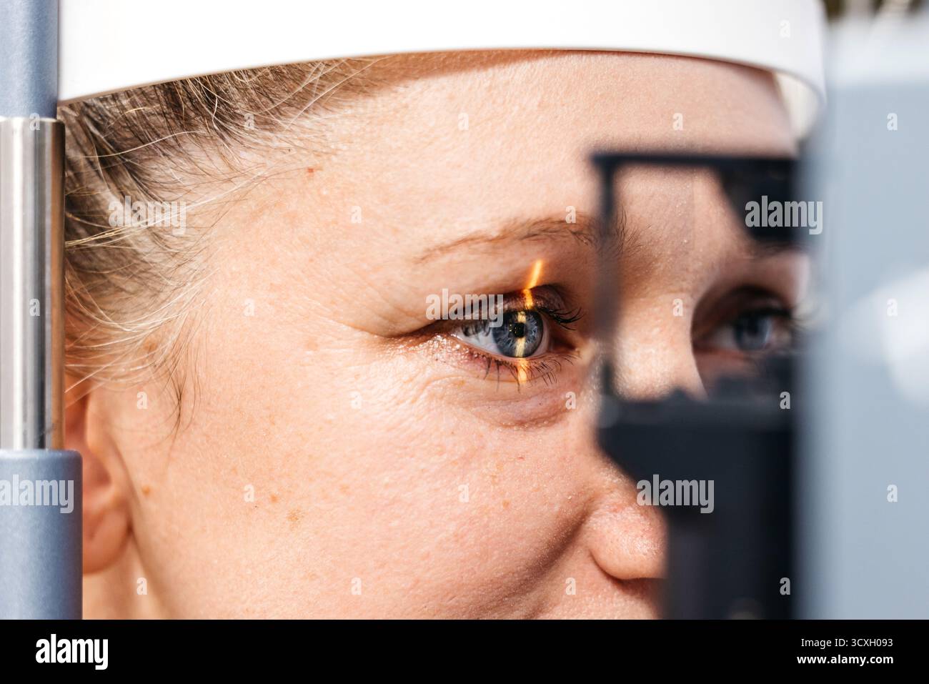 Female patient is receiving a thorough vision examination using a slit ...
