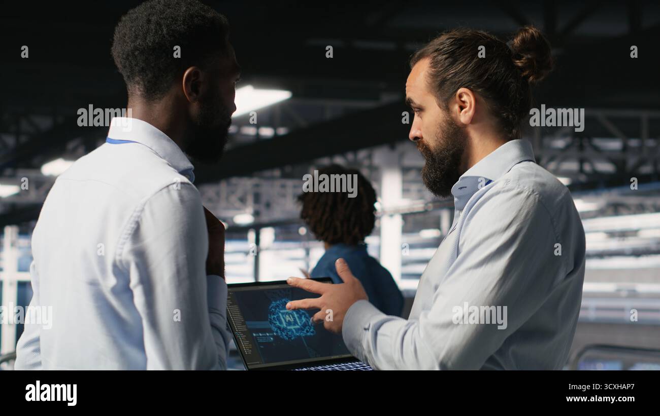Server farm coworkers doing infrastructure AI machine learning automatization. Data center computer scientists collaborating to maintain servers using artificial intelligence Stock Photo