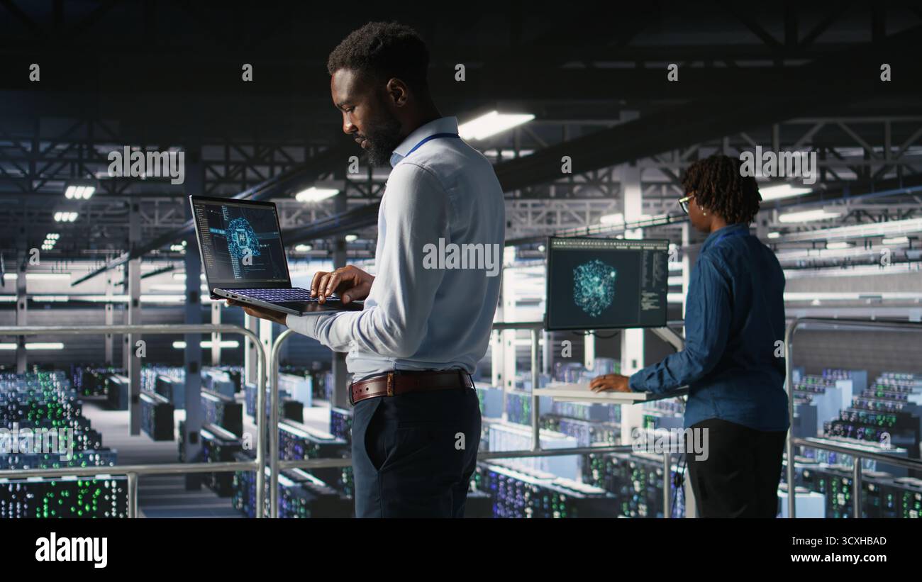 Server hub teamworking IT experts visualizing large language model architecture using notebook. Data center system administrators on industrial platform collaborating on tasks using laptop Stock Photo