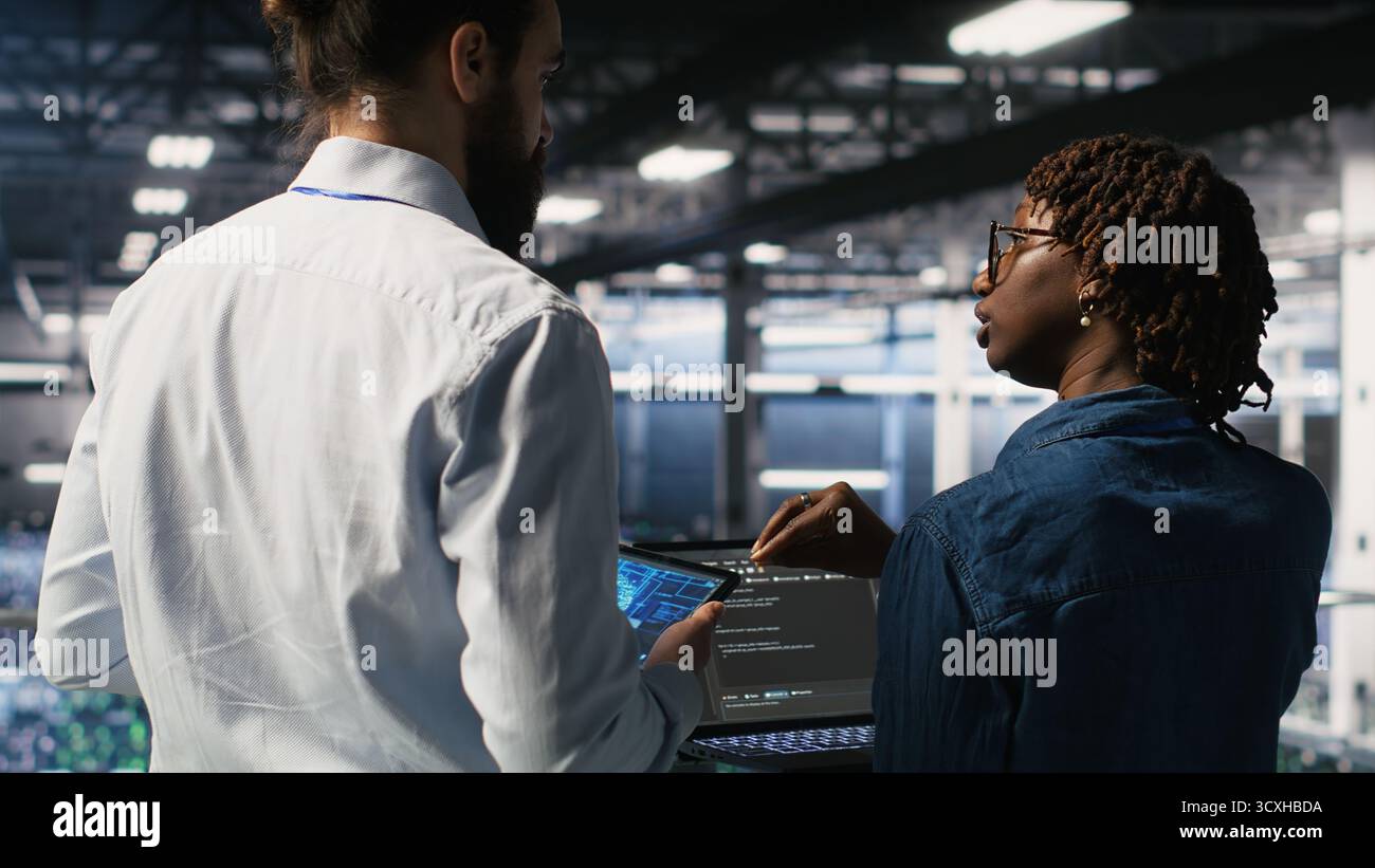 Data center system administrators performing maintenance on supercomputers used for AI. Engineering team managing server hub rigs used for deep learning training Stock Photo