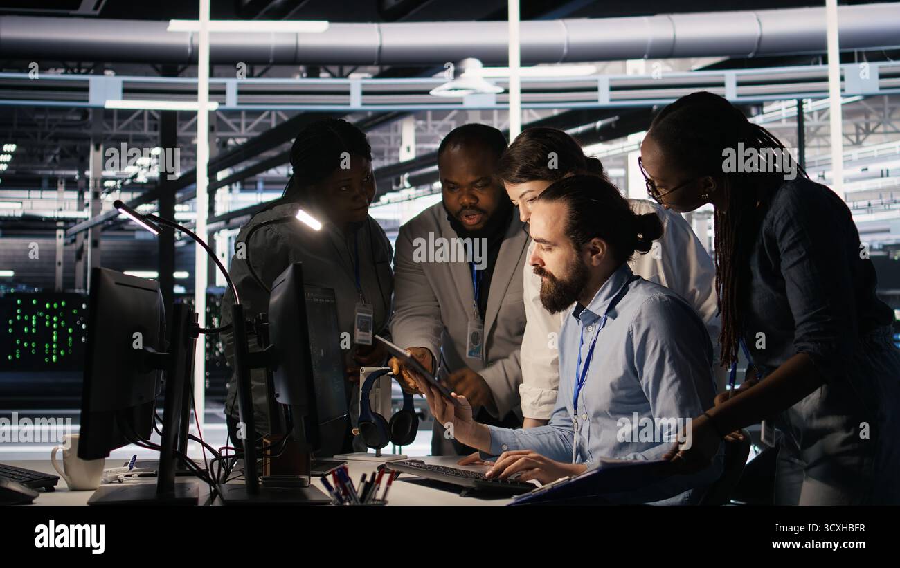 Admins doing brainstorming in server hub, reviewing machine learning code and LLM visualization dashboards. Data center IT experts using computer to monitor AI infrastructure performance, camera A Stock Photo