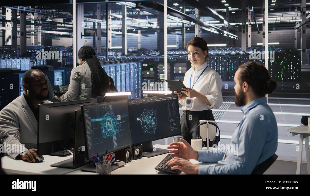 Data center team of technicians working on neural network software development. Server hub colleagues implementing deep learning artificial intelligence technology in workplace, camera A Stock Photo