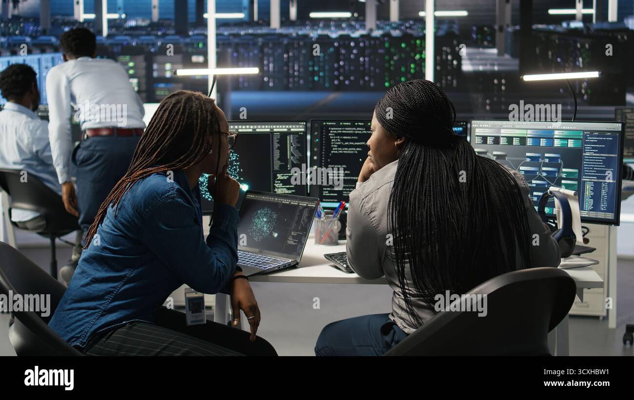 Data center coworkers doing brainstorming, using artificial intelligence machine learning models to configure equipment. IT experts cooperating in server farm, working on optimizing systems, camera A Stock Photo