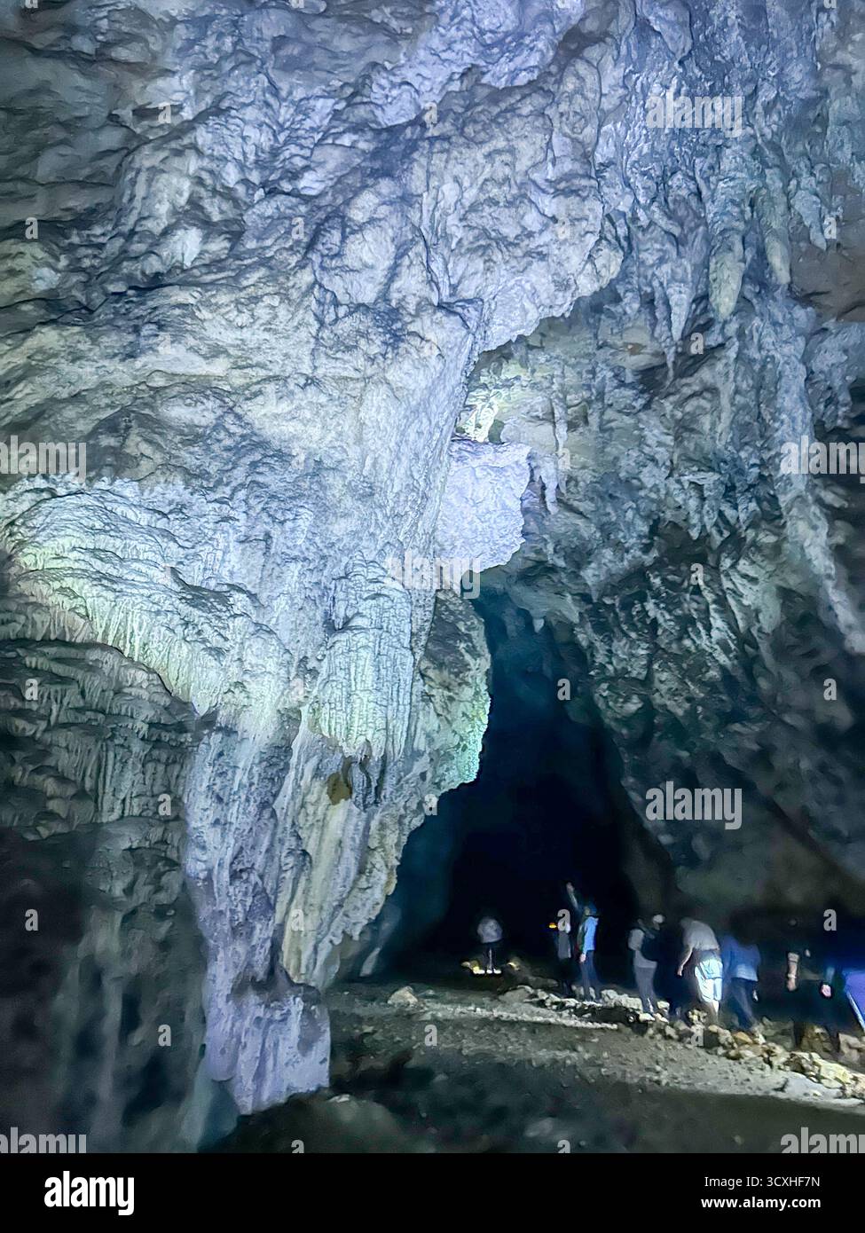 Visitors explore the stunning Ice Cave in Uvac Canyon, Serbia, showcasing majestic limestone formations and dramatic underground scenery. - Smartphone Captured Stock Image