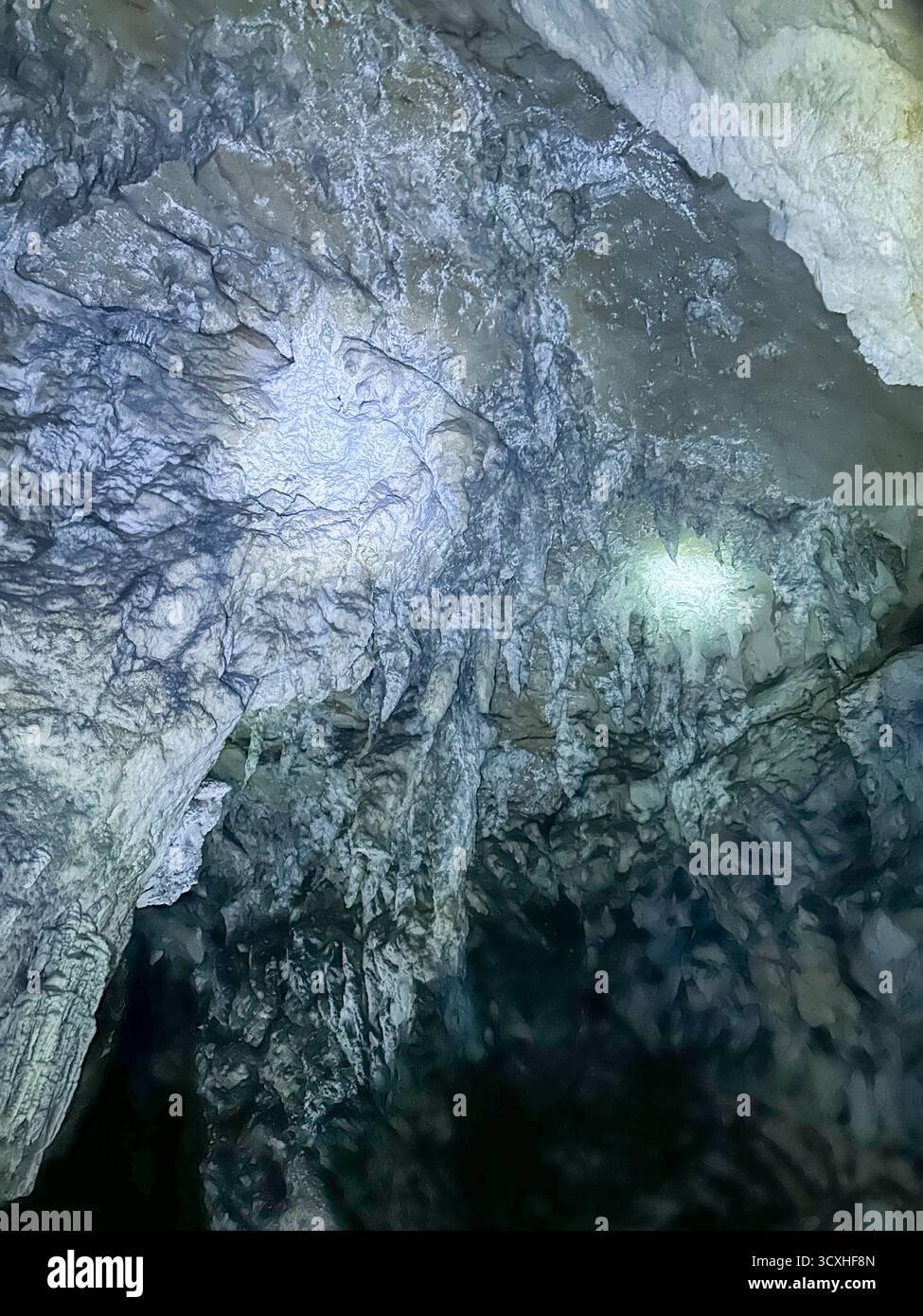 Stunning interior of the Ice Cave in Uvac Canyon, Serbia, featuring natural rock formations and glistening mineral textures illuminated by light. - Smartphone Captured Stock Image