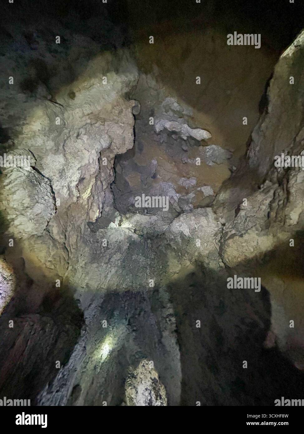 Mysterious interior of the Ice Cave in Uvac Canyon, showcasing textured limestone formations illuminated by artificial light deep underground. - Smartphone Captured Stock Image