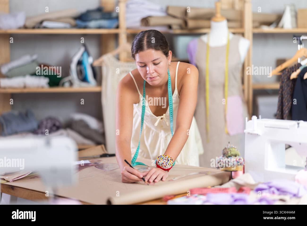 Using curve ruler, woman tailor draws dress diagram scheme on paper ...