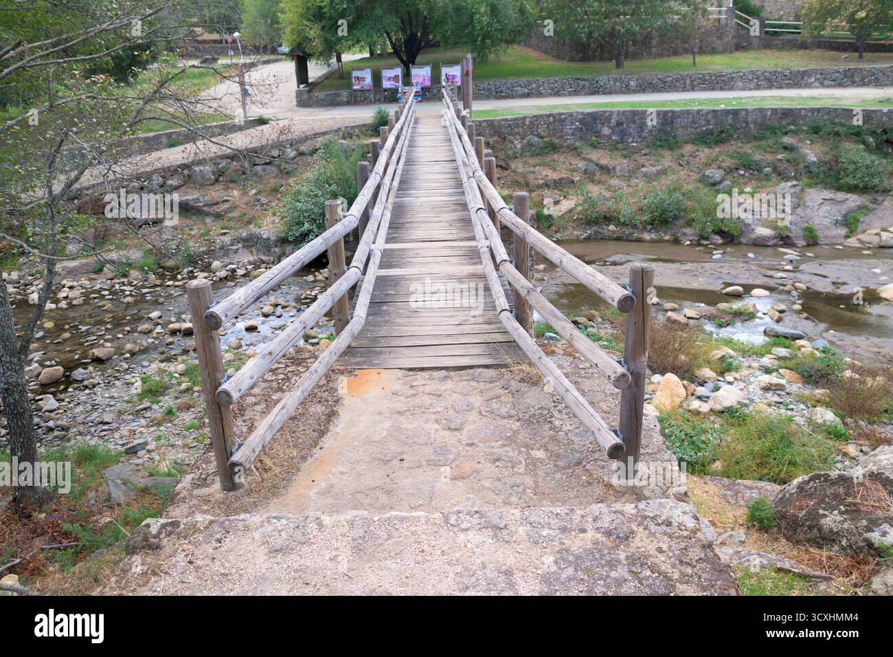 Rustic wooden bridge crossing a shallow stream in a peaceful mountain ...