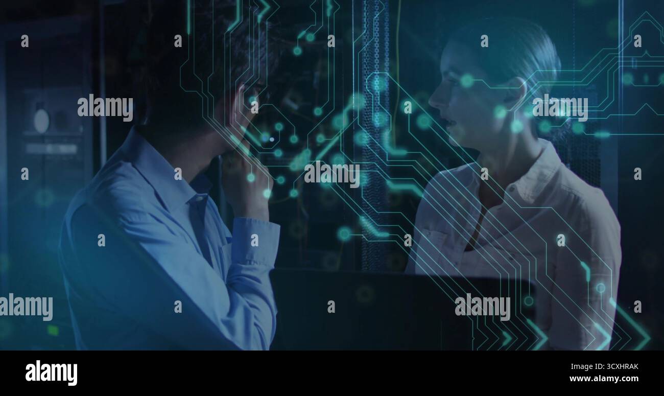Discussing IT professionals analyzing data flow in server room with open laptop, circuitry overlay Stock Photo