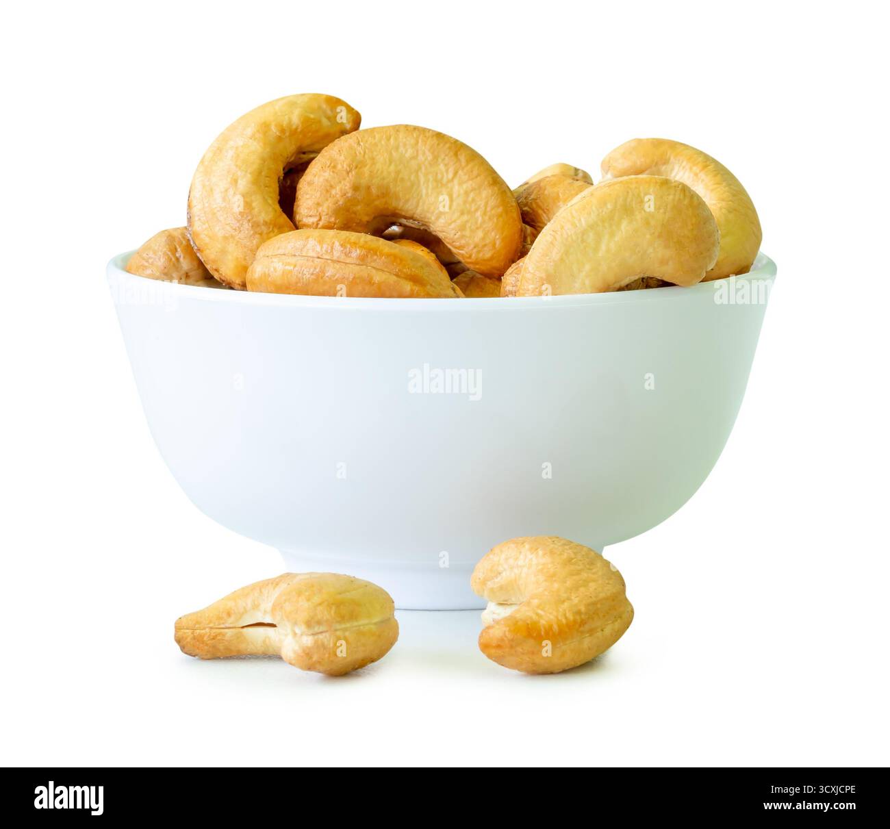 Brown cashew nuts in stack in small white cup are isolated with clipping path. Stock Photo