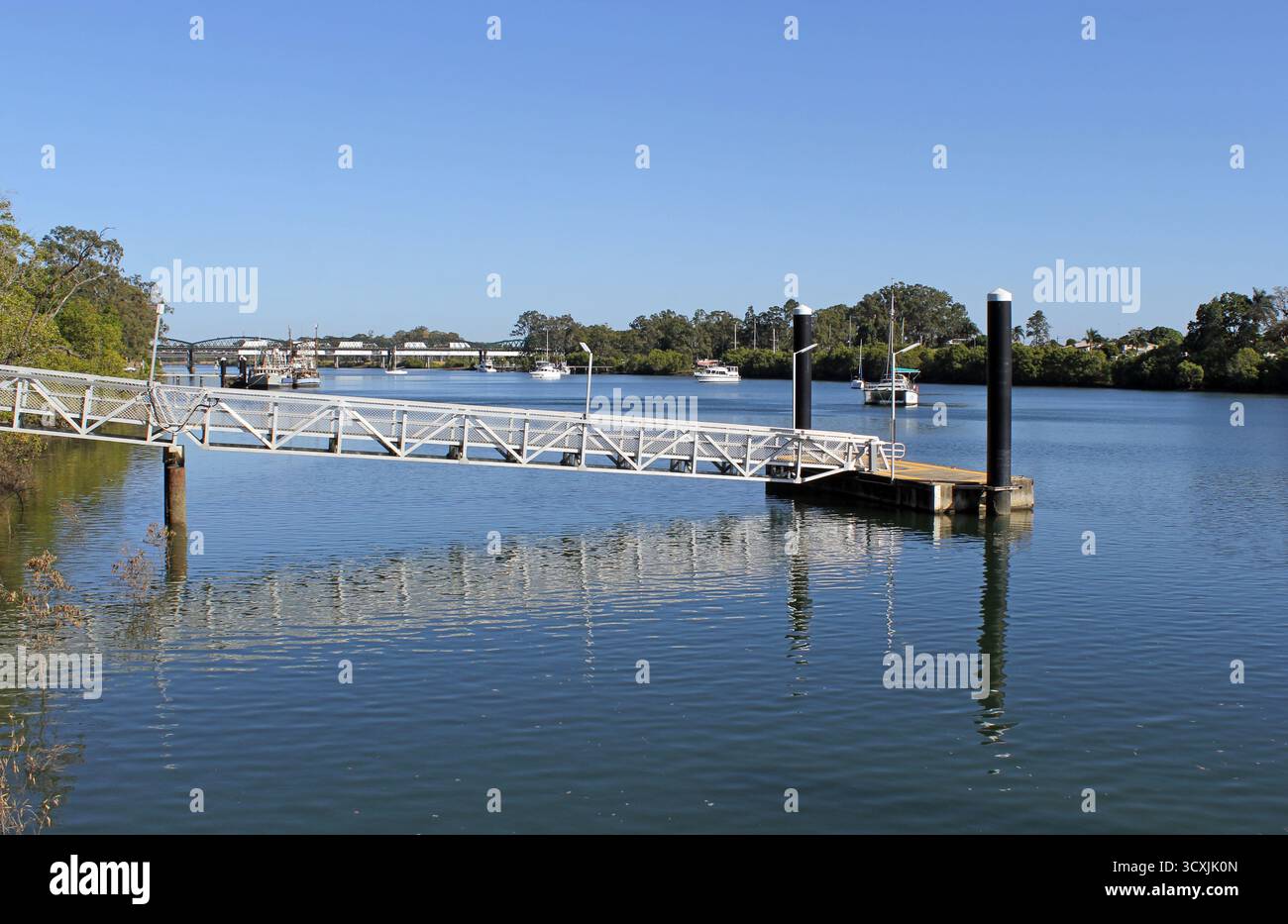 Boat ramp at the Burnett River with boats, trees and a bridge under a ...