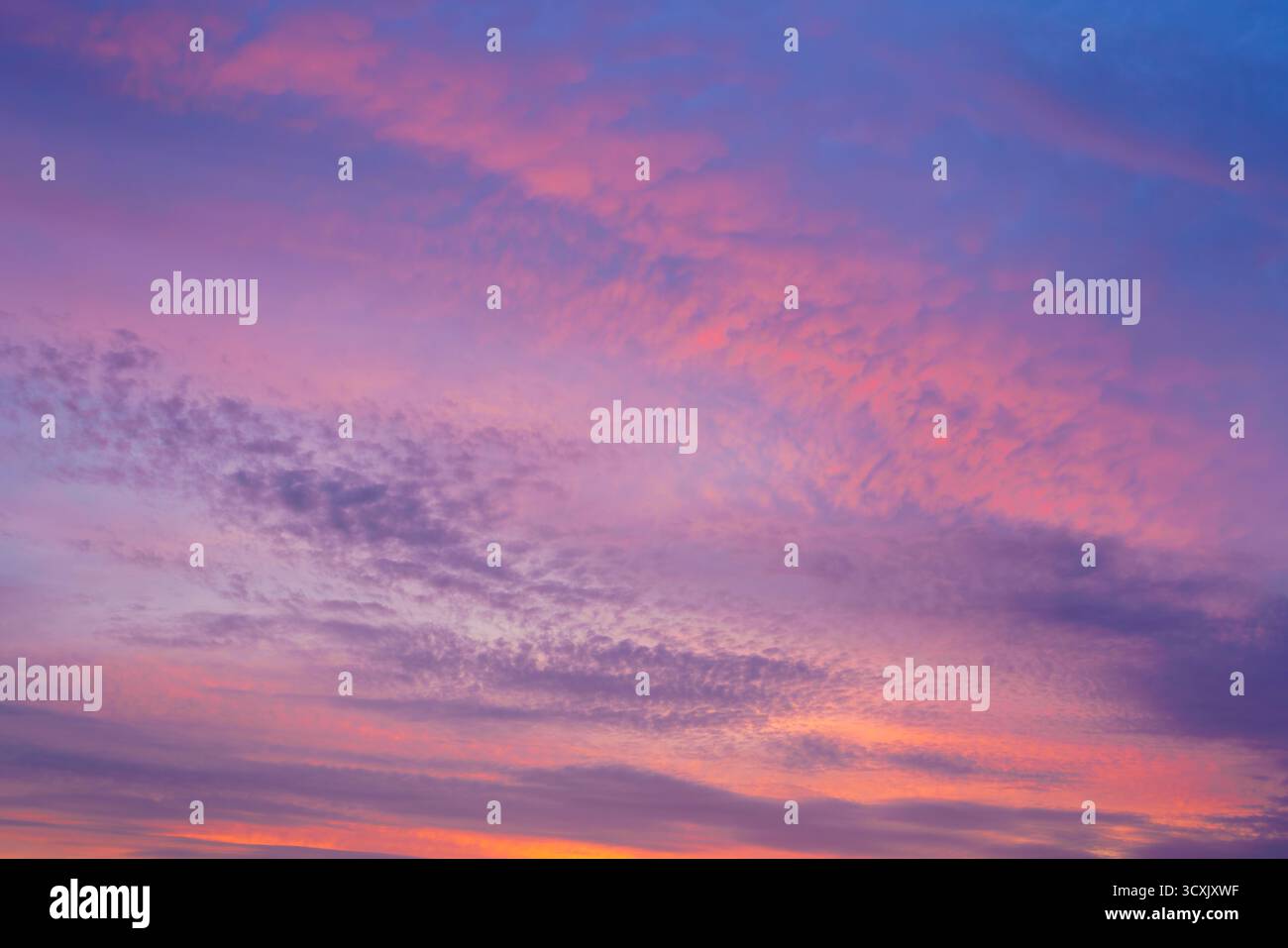 A beautiful sunset or sunrise sky with vibrant clouds changing from purple to orange is perfect for an abstract or nature background. Stock Photo