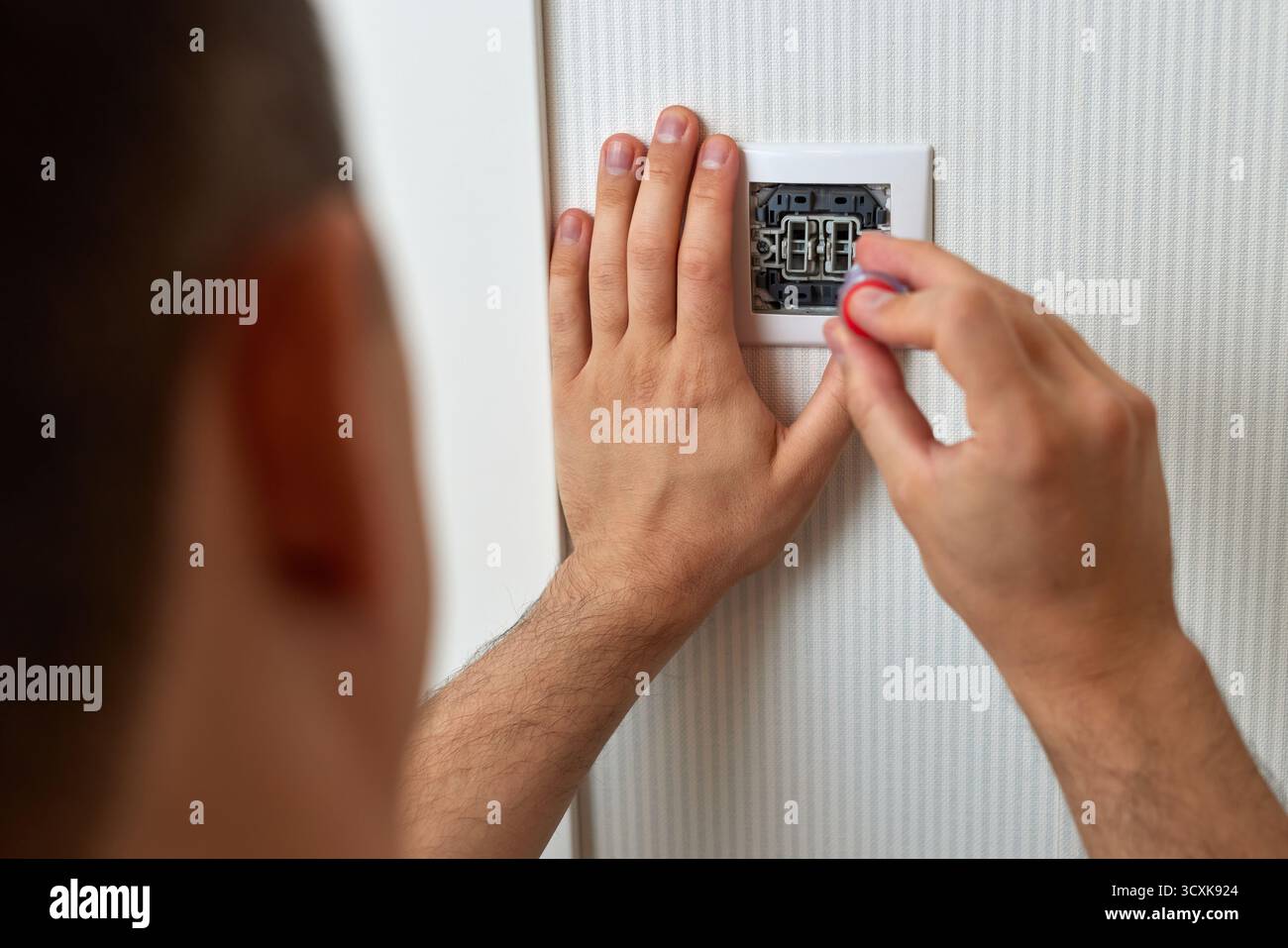 electrician working on light switch using screwdriver inside, close-up Stock Photo
